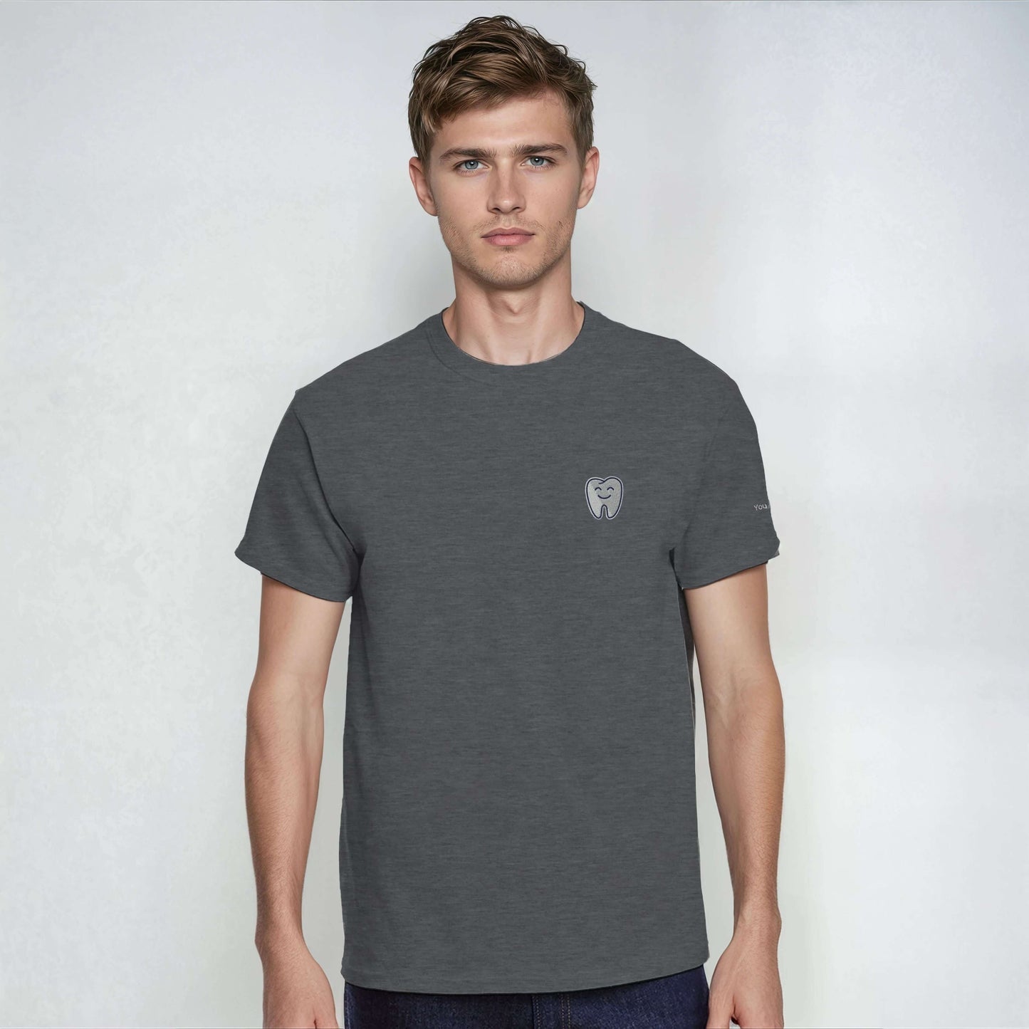 Model wearing a Personalized Heavyweight Unisex Crewneck T-Shirt with Smiling Tooth Embroidery in dark gray.